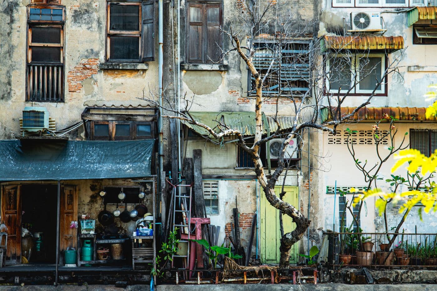 Weathered heritage facade with plants in Bangkok's Talad Noi neighborhood